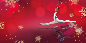 A Brigh Red Background with Gold snowflakes scattered on it. In the forground an male ballet dance leapes across the image in a red millitary style jacket and white ballet tights, with a fmele dance leaping in the opposite direction in a decorative costume wearing a red cloak trimmed in white fur, as if a reflection of the male dancer.